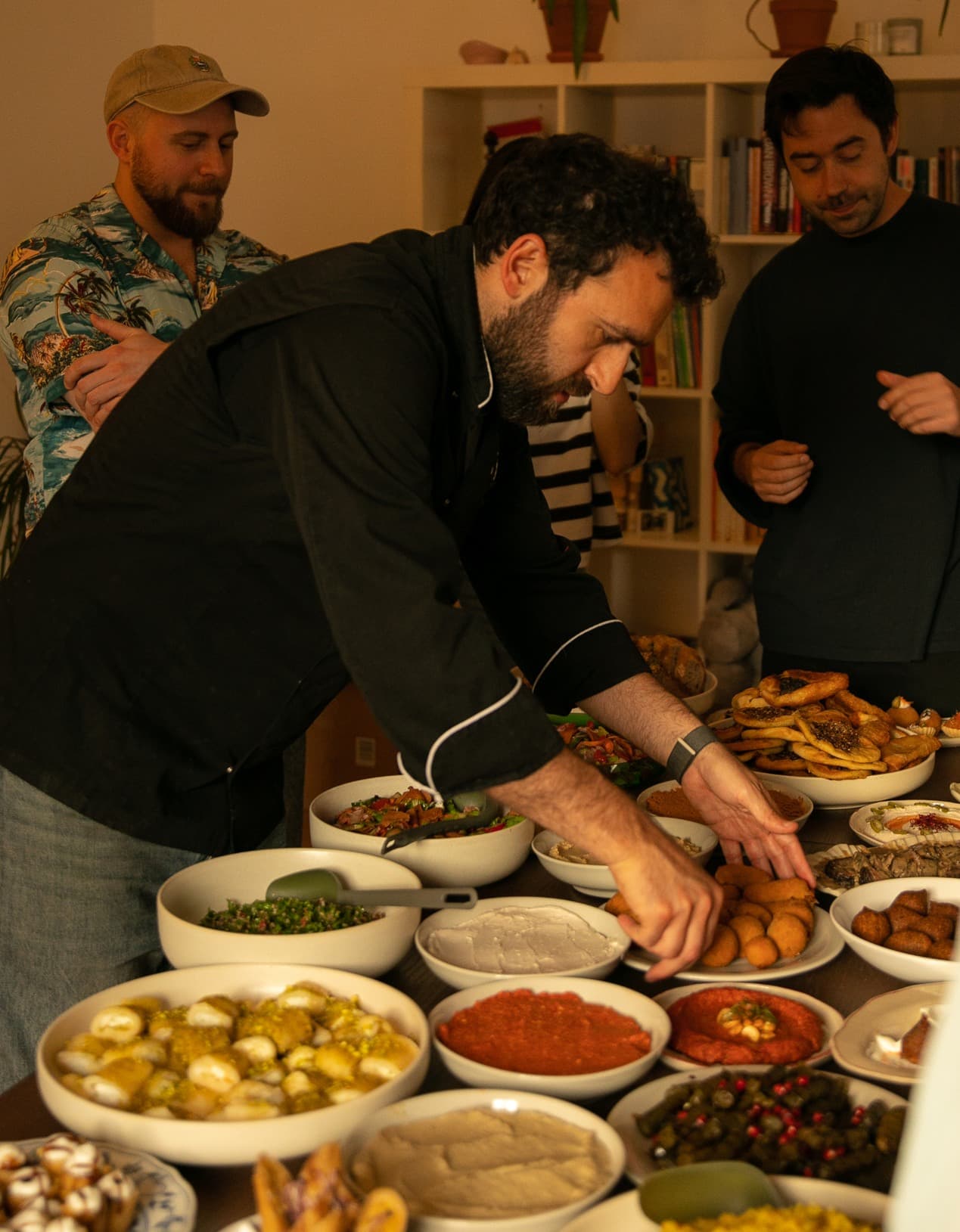 Sam Darwish and two colleagues preparing an array of mezze dishes at a table.